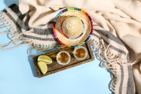 Shots of tequila and sombrero hat on blue background