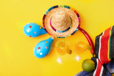 Shots of tequila, lime and maracas on yellow background