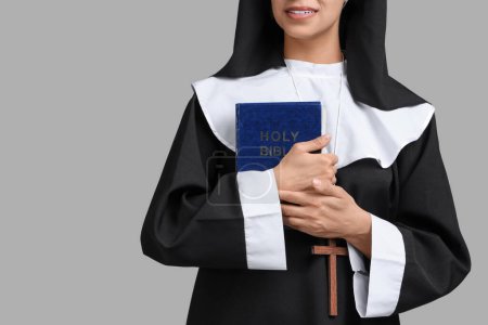 Photo for Young nun with Bible on grey  background - Royalty Free Image