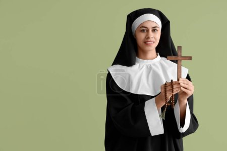 Young nun with cross and rosary beads on green background