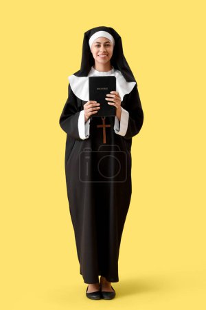 Téléchargez les photos : Jeune religieuse avec Bible sur fond jaune - en image libre de droit