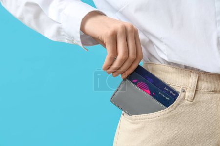Photo for Young woman with credit card holder in pocket on blue background - Royalty Free Image