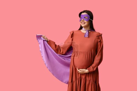 Téléchargez les photos : Belle jeune femme enceinte en costume de super-héros sur fond rose - en image libre de droit
