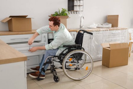 Photo for Young man in wheelchair repairing kitchen drawer at home - Royalty Free Image