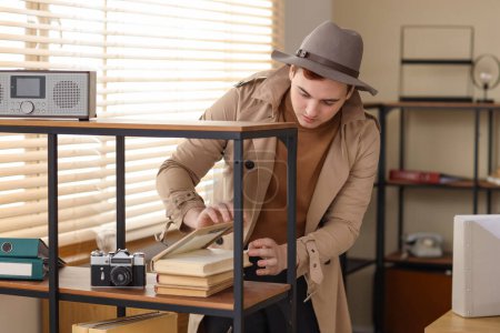 Téléchargez les photos : Homme espion regarder à travers les livres dans le bureau - en image libre de droit