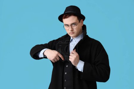 Foto de Espía masculino con pistola sobre fondo azul - Imagen libre de derechos