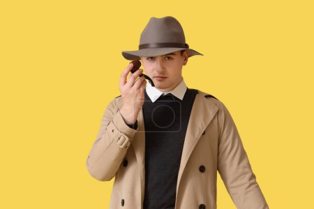 Téléchargez les photos : Homme espion avec pipe à fumer sur fond jaune - en image libre de droit