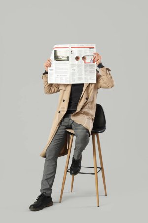Téléchargez les photos : Homme espion avec journal assis sur fond clair - en image libre de droit