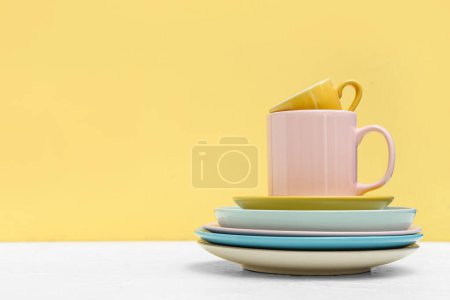 Téléchargez les photos : Ensemble de tasses et assiettes propres sur la table sur fond jaune - en image libre de droit