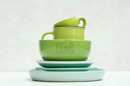 Téléchargez les photos : Empilement de vaisselle verte propre sur fond blanc - en image libre de droit