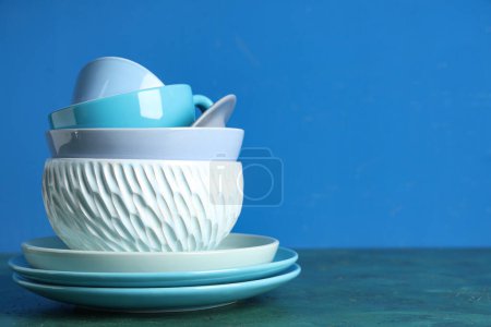 Téléchargez les photos : Empilement de vaisselle propre sur la table sur fond bleu - en image libre de droit