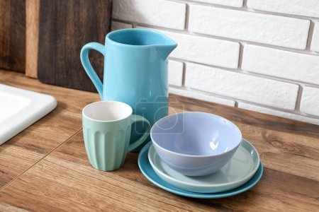 Téléchargez les photos : Empilement de vaisselle bleue propre sur une table en bois près d'un mur de briques blanches - en image libre de droit