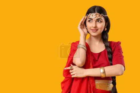 Téléchargez les photos : Belle jeune femme indienne heureuse en sari sur fond jaune - en image libre de droit