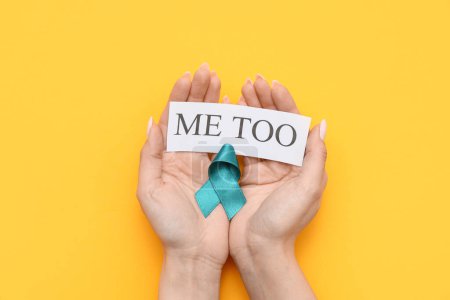 Photo for Female hands holding teal ribbon and paper with text ME TOO on yellow background. Sexual Assault Awareness Month - Royalty Free Image