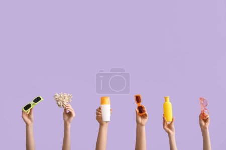 Female hands with sunscreens, sunglasses and coral on violet background. Travel concept.