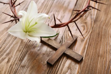 Foto de Lirio blanco, corona de espinas y cruz sobre fondo de madera, primer plano - Imagen libre de derechos