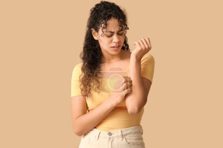 Foto de Joven mujer afroamericana con alergia a la piel arañándose sobre fondo marrón - Imagen libre de derechos
