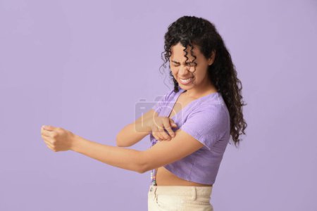 Foto de Joven mujer afroamericana con alergia a la piel arañándose sobre fondo lila - Imagen libre de derechos