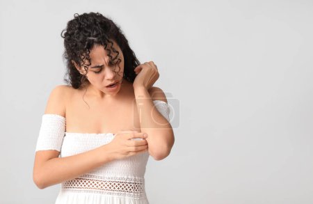 Foto de Joven mujer afroamericana con alergia a la piel arañándose sobre fondo gris - Imagen libre de derechos