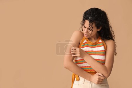 Foto de Joven mujer afroamericana con alergia a la piel arañándose sobre fondo marrón - Imagen libre de derechos