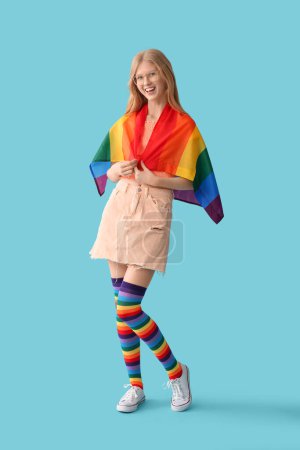 Schöne junge glückliche Frau in Regenbogenstrümpfen mit LGBT-Flagge auf blauem Hintergrund