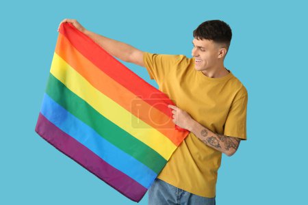 Guapo joven feliz hombre con banderas LGBT sobre fondo azul