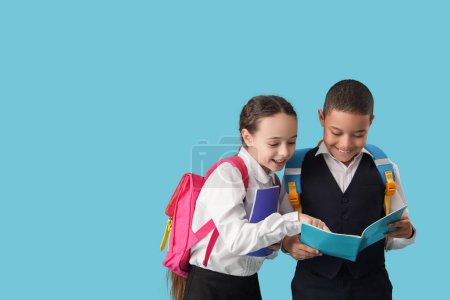 Photo for Happy little pupils with backpacks and notebooks on blue background - Royalty Free Image