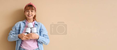 Foto de Mujer feliz con latas de pintura sobre fondo beige con espacio para texto - Imagen libre de derechos