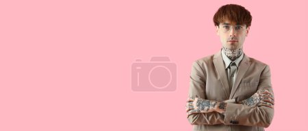 Young tattooed businessman on pink background with space for text