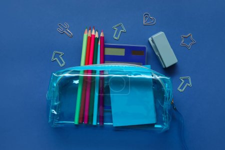 Foto de Caja de lápiz con diferentes artículos de papelería de la escuela y cuaderno sobre fondo azul - Imagen libre de derechos