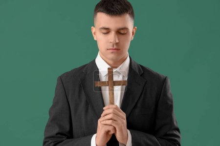 Foto de Joven con cruz de madera rezando sobre fondo verde - Imagen libre de derechos