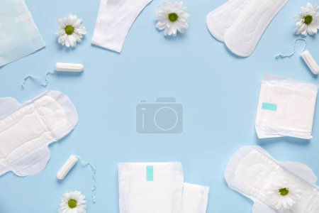 Téléchargez les photos : Coussinets menstruels avec fleurs de chrysanthème et tampons sur fond bleu - en image libre de droit
