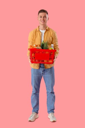 Téléchargez les photos : Jeune homme avec panier plein sur fond rose - en image libre de droit