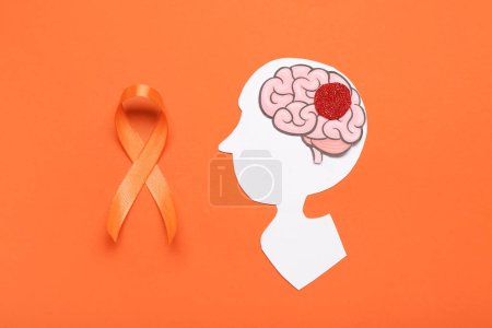 Paper human head with brain and orange ribbon on color background. Multiple Sclerosis Awareness Month
