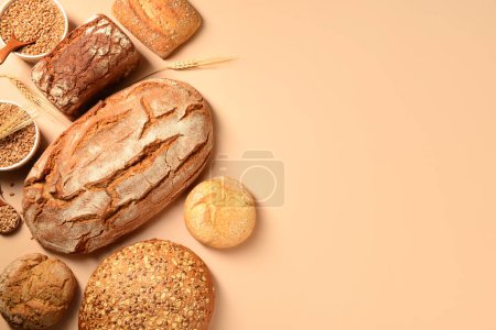 Photo for Loaves of fresh bread with buns and wheat spikelets on beige background - Royalty Free Image