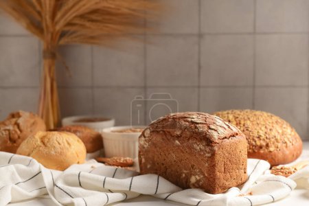 Photo for Loaves of fresh bread and buns against grey tile wall - Royalty Free Image