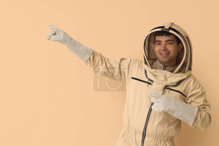 Male beekeeper pointing at something on beige background