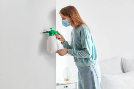 Mujer joven quitando el moho de la pared en el dormitorio