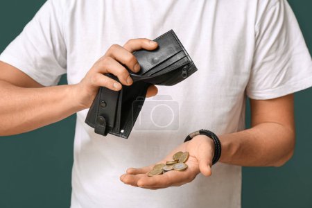 Man emptying wallet with few coins on green background, closeup