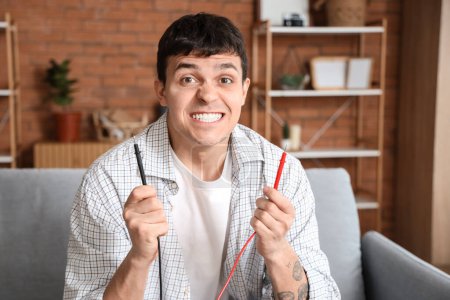 Hombre joven electrocutado con cables en casa, primer plano