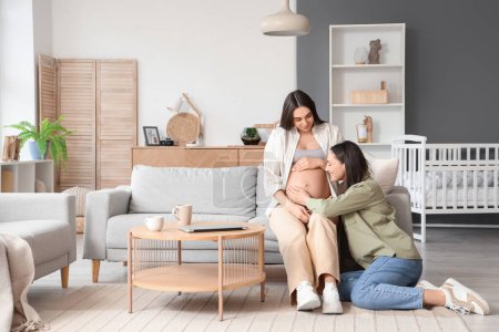 Junge lesbische Frau mit ihrer schwangeren Frau zu Hause