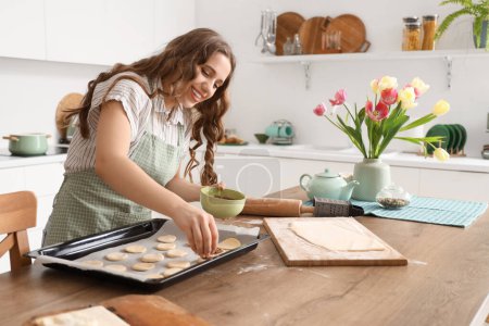 Téléchargez les photos : Jeune femme faisant des biscuits au chocolat à table dans la cuisine - en image libre de droit