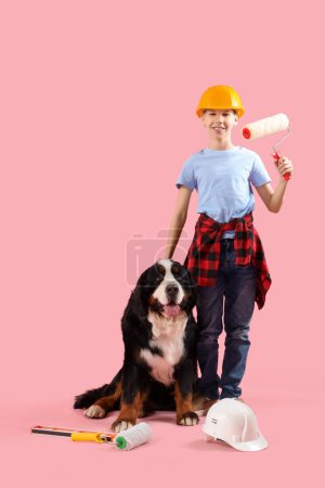 Téléchargez les photos : Petit garçon avec rouleau de peinture et chien de montagne bernois sur fond rose - en image libre de droit