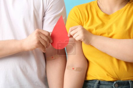 Donors with applied medical patches and paper blood drop on blue background