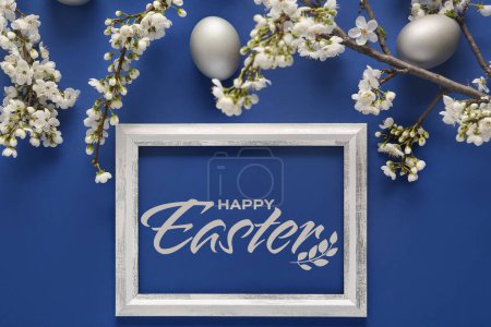 Photo for Beautiful Easter greeting card with frame, blooming branches and eggs on blue background - Royalty Free Image