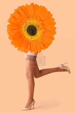 Téléchargez les photos : Collage avec gerbera fleur et jambes de jeune femme en bas nus et talons hauts sur fond beige - en image libre de droit