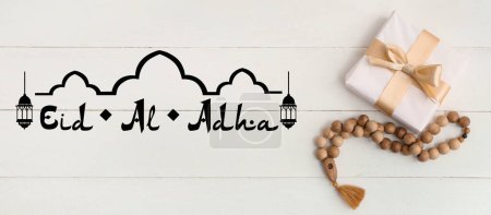 Téléchargez les photos : Coffret cadeau, perles de prière et texte EID AL ADHA sur fond de bois blanc - en image libre de droit