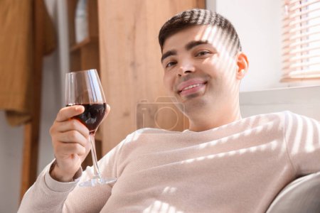 Photo for Young man with glass of red wine sitting on sofa at home, closeup - Royalty Free Image