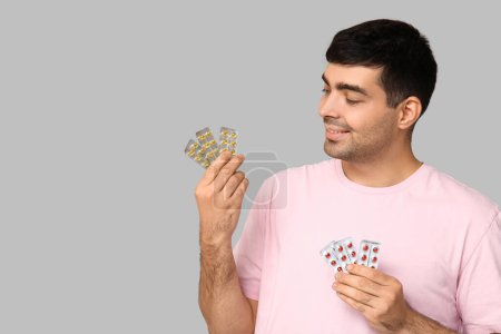 Foto de Hombre joven con ampollas de píldoras de vitamina A sobre fondo claro - Imagen libre de derechos