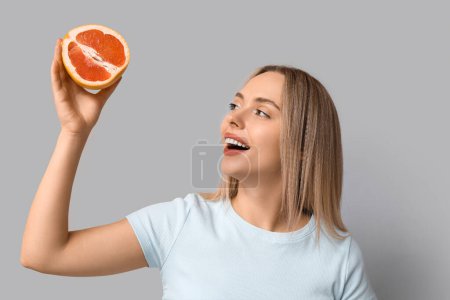 Young woman with grapefruit on light background, closeup